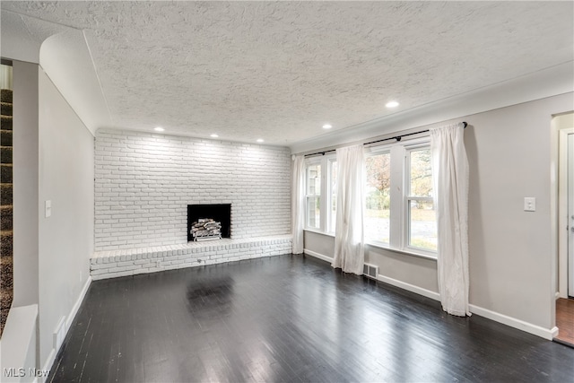 unfurnished living room featuring brick wall, a fireplace, dark wood-type flooring, and a textured ceiling