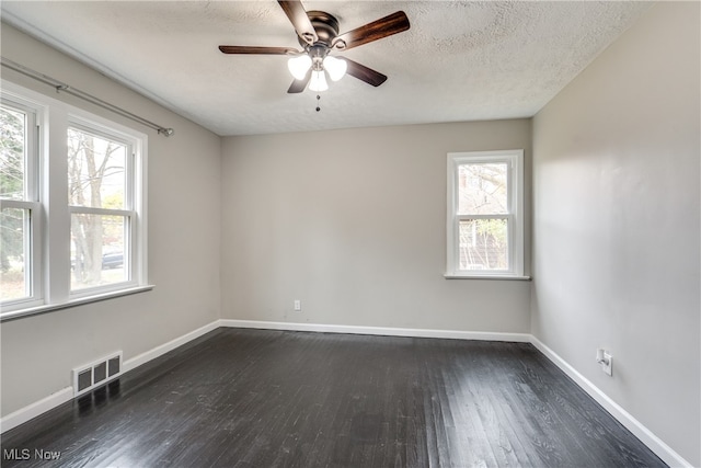 spare room with a textured ceiling, ceiling fan, dark hardwood / wood-style flooring, and plenty of natural light