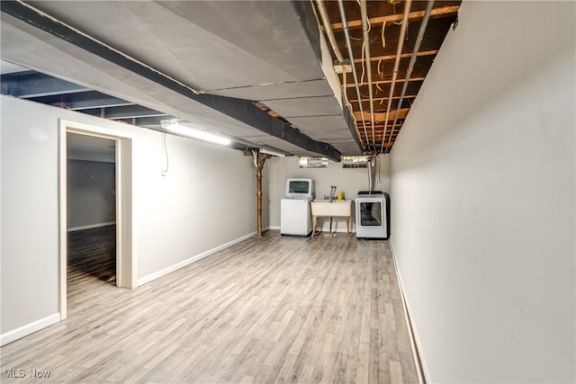 basement featuring light hardwood / wood-style flooring, washer / clothes dryer, and sink