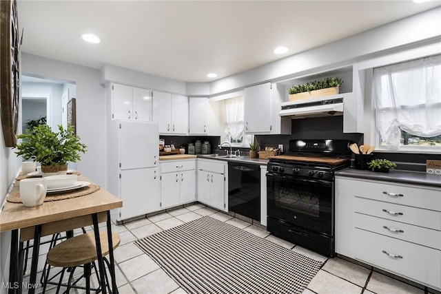 kitchen with light tile patterned flooring, white cabinets, sink, and black appliances