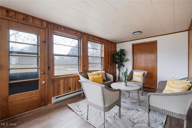 interior space with crown molding, a baseboard radiator, wooden walls, and hardwood / wood-style floors