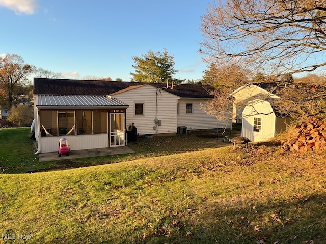 back of property featuring a shed, a lawn, cooling unit, and a sunroom