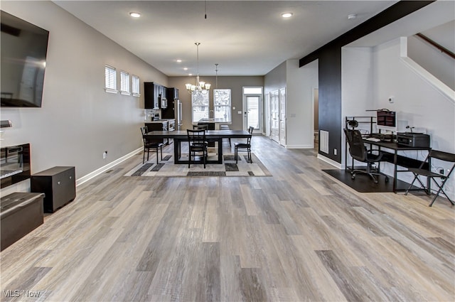 dining space with light wood-type flooring and an inviting chandelier