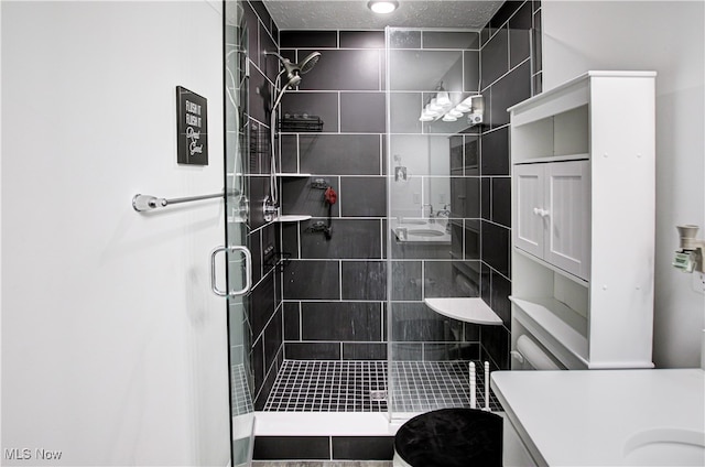 bathroom featuring a shower with door, vanity, a textured ceiling, and toilet