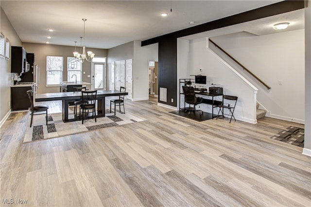 dining area featuring sink, a chandelier, and light wood-type flooring