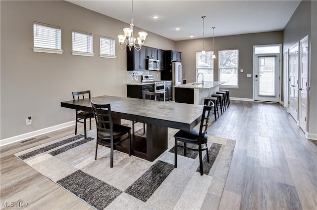 dining room featuring a chandelier, light hardwood / wood-style flooring, and sink