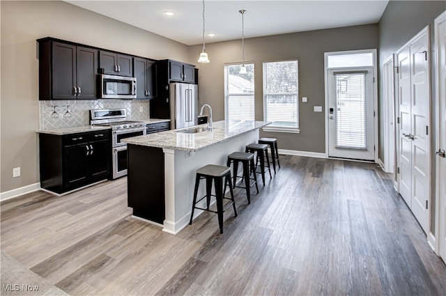 kitchen featuring a kitchen breakfast bar, an island with sink, light hardwood / wood-style flooring, and stainless steel appliances