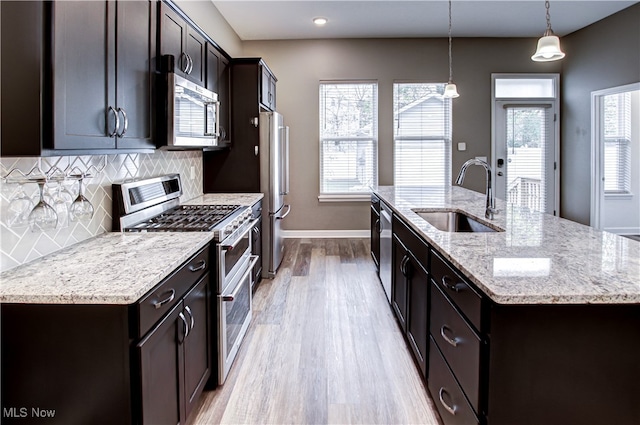 kitchen featuring sink, a healthy amount of sunlight, an island with sink, decorative light fixtures, and appliances with stainless steel finishes