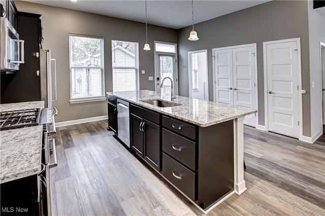 kitchen with sink, hardwood / wood-style floors, decorative light fixtures, a center island with sink, and appliances with stainless steel finishes