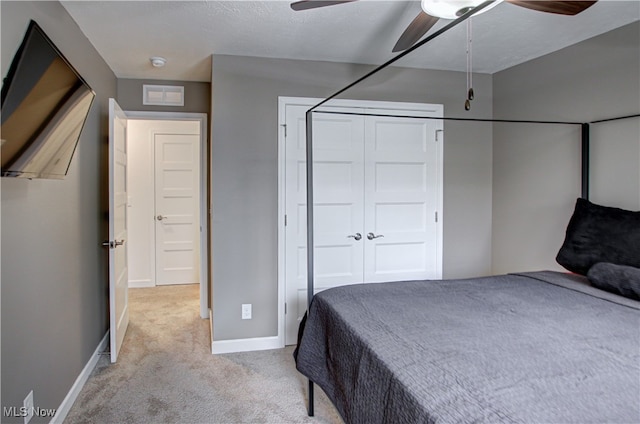 bedroom with a closet, ceiling fan, light carpet, and a textured ceiling