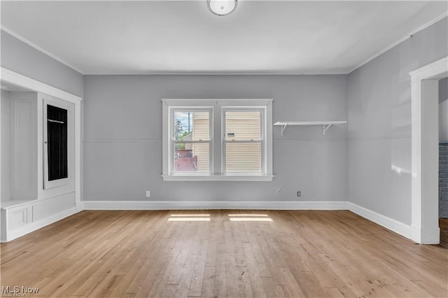 spare room featuring crown molding and light wood-type flooring