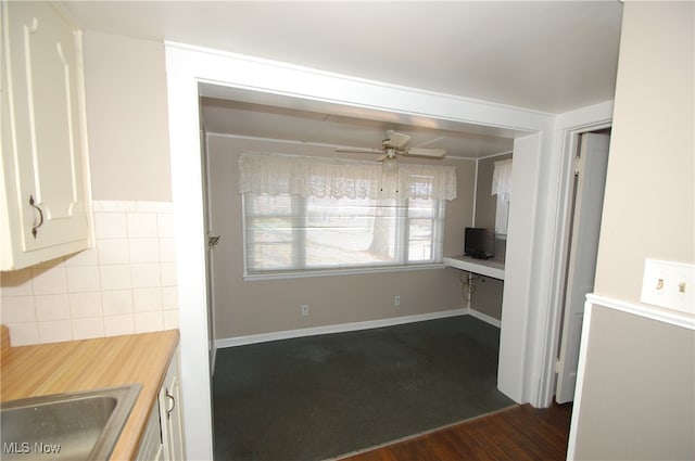 kitchen with ceiling fan, built in desk, tile walls, white cabinets, and dark hardwood / wood-style floors