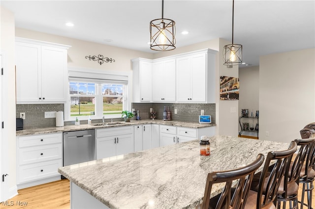 kitchen featuring pendant lighting, stainless steel dishwasher, and a breakfast bar area