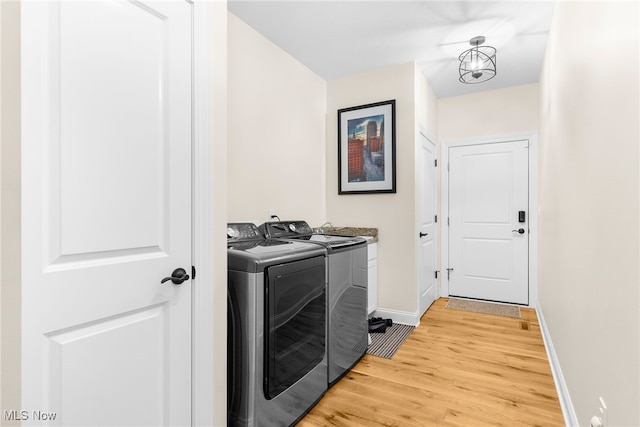 laundry area featuring cabinets, wood-type flooring, separate washer and dryer, and a notable chandelier