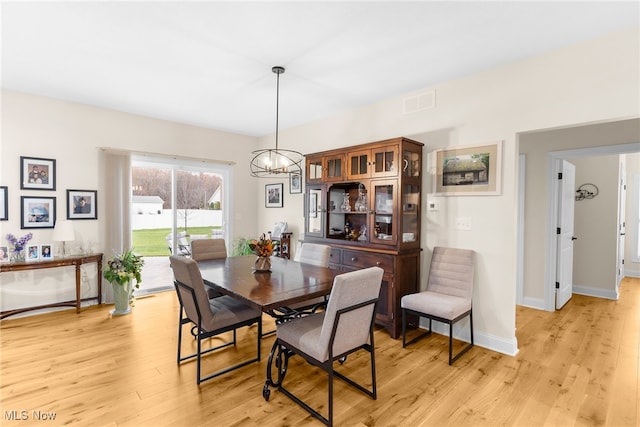 dining room with light hardwood / wood-style flooring and an inviting chandelier