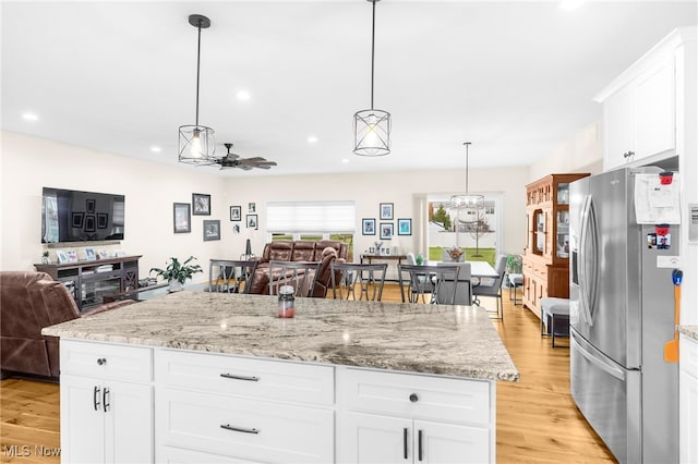 kitchen featuring white cabinets, stainless steel fridge, light wood-type flooring, and a kitchen island