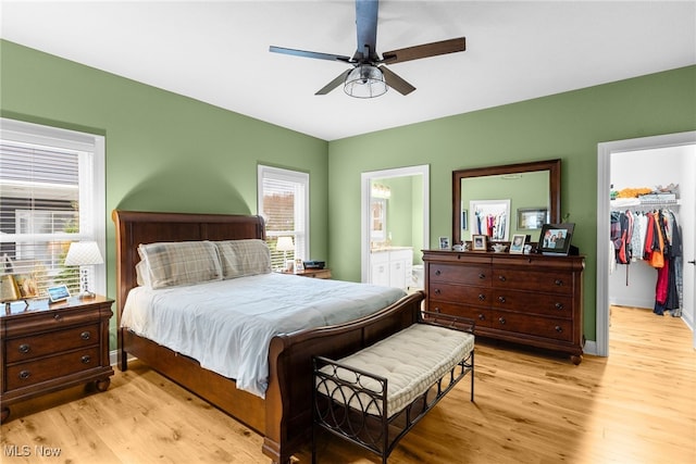 bedroom featuring a walk in closet, ensuite bathroom, a closet, ceiling fan, and light wood-type flooring