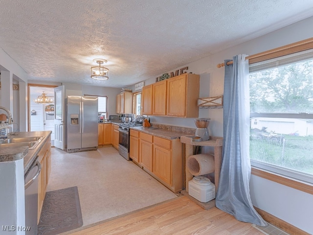 kitchen with a textured ceiling, stainless steel appliances, light hardwood / wood-style floors, and sink