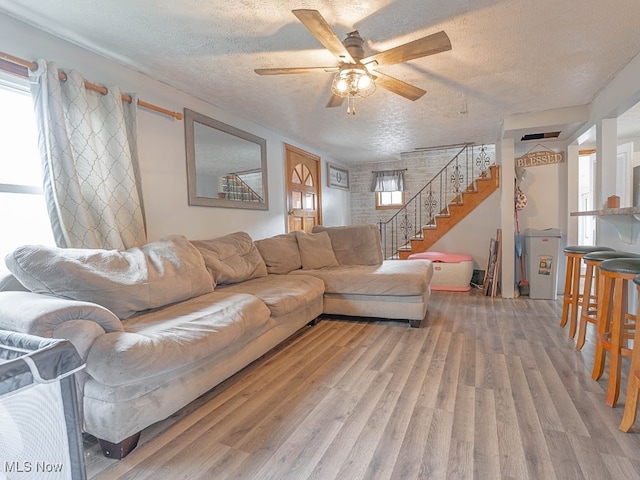 living room with ceiling fan, wood-type flooring, and a textured ceiling