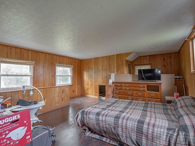 bedroom with a textured ceiling, dark hardwood / wood-style floors, and wooden walls