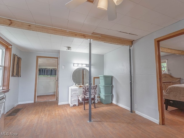 interior space with wood-type flooring, ceiling fan, and beam ceiling