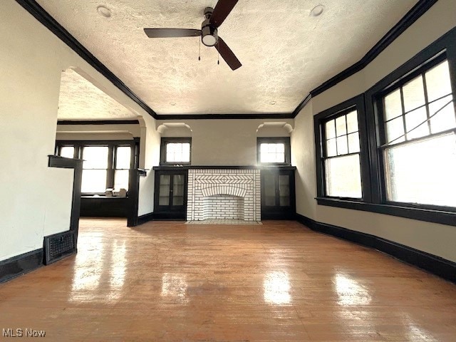 unfurnished living room featuring crown molding, ceiling fan, a textured ceiling, and hardwood / wood-style flooring