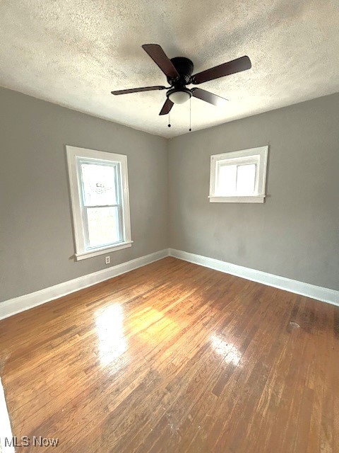 unfurnished room with wood-type flooring, a textured ceiling, and ceiling fan