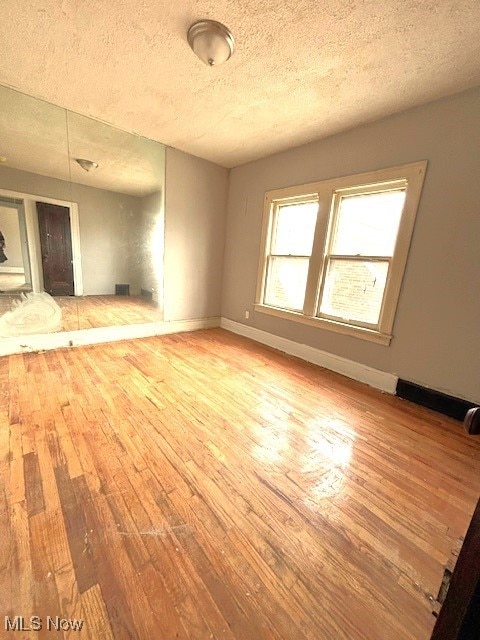 unfurnished living room with a textured ceiling and light hardwood / wood-style flooring