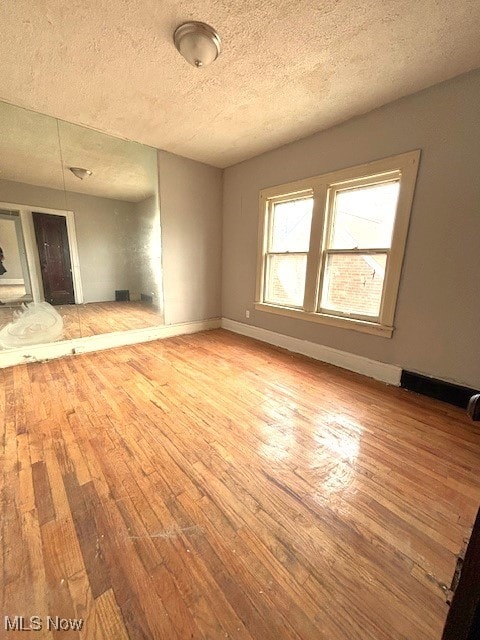 unfurnished living room with wood-type flooring and a textured ceiling