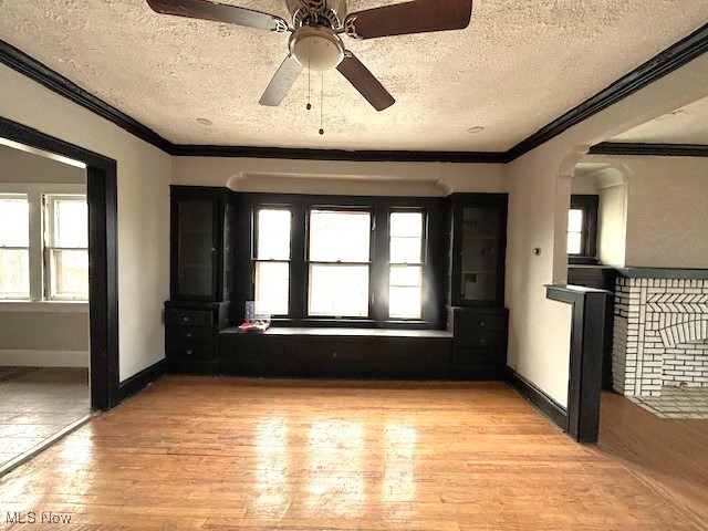 unfurnished room with ceiling fan, light hardwood / wood-style flooring, a textured ceiling, and ornamental molding