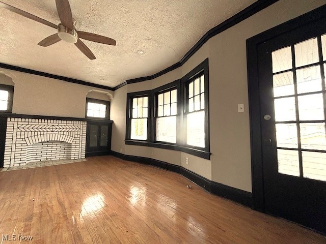 unfurnished living room featuring ceiling fan, hardwood / wood-style flooring, crown molding, and a textured ceiling