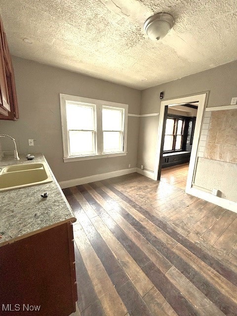 unfurnished dining area with sink, dark wood-type flooring, and a textured ceiling