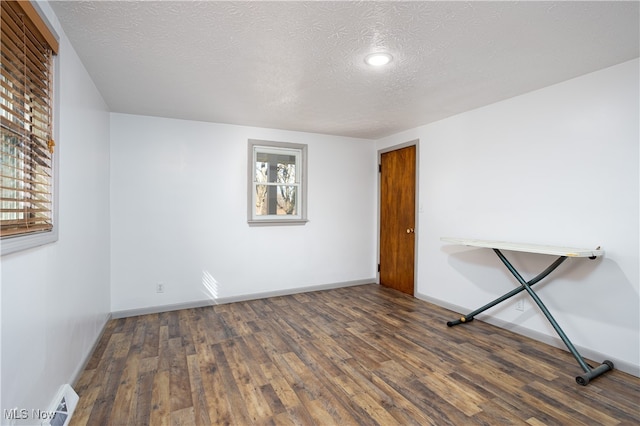 empty room with dark hardwood / wood-style floors and a textured ceiling