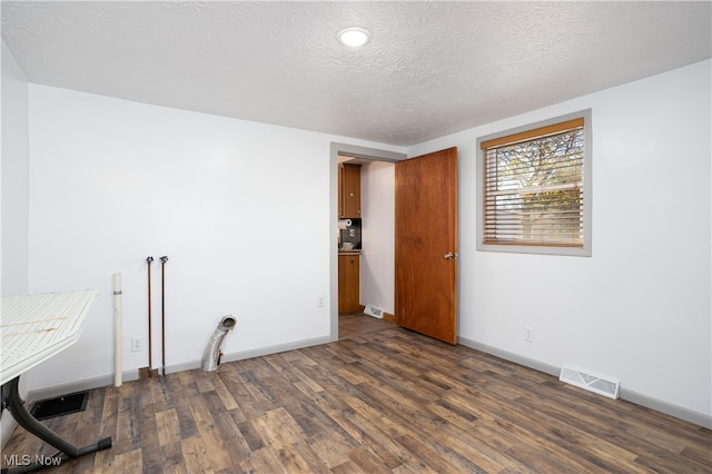 empty room featuring a textured ceiling and dark hardwood / wood-style floors