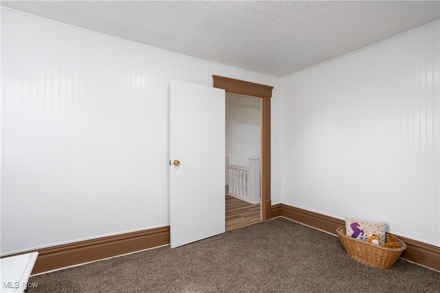 unfurnished room with dark colored carpet and a textured ceiling