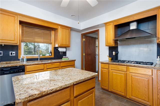 kitchen with sink, appliances with stainless steel finishes, tasteful backsplash, wall chimney exhaust hood, and light stone counters