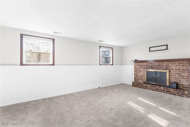 unfurnished living room with carpet, a healthy amount of sunlight, and a brick fireplace