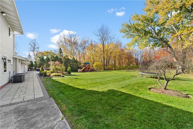 view of yard with a playground, central AC unit, a trampoline, and a patio