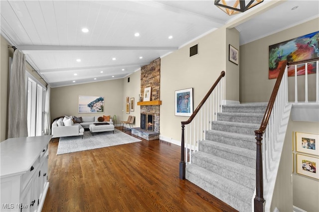 living room featuring dark hardwood / wood-style flooring, vaulted ceiling with beams, a fireplace, and ornamental molding