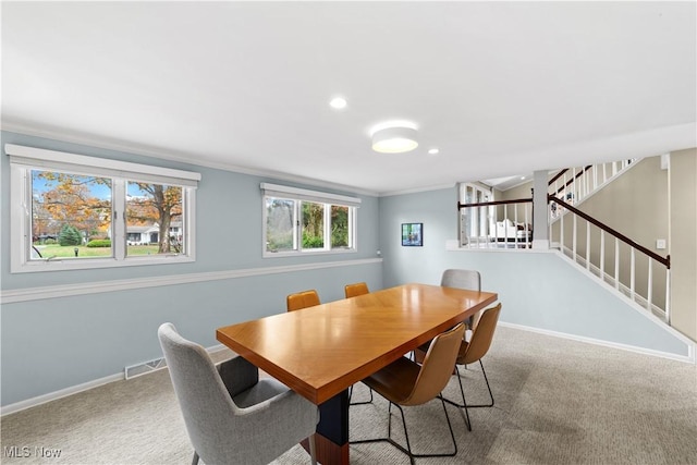 carpeted dining space featuring ornamental molding