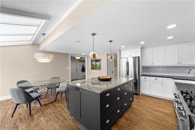 kitchen featuring a kitchen island, pendant lighting, wood-type flooring, white cabinets, and stainless steel appliances