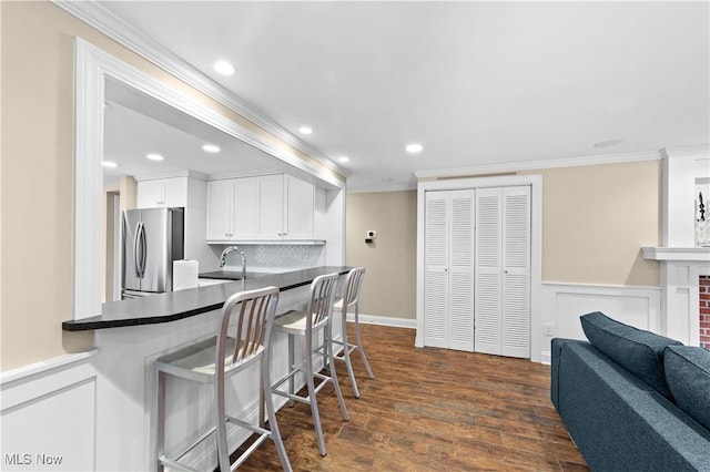 kitchen featuring dark wood-type flooring, stainless steel refrigerator, ornamental molding, decorative backsplash, and white cabinets