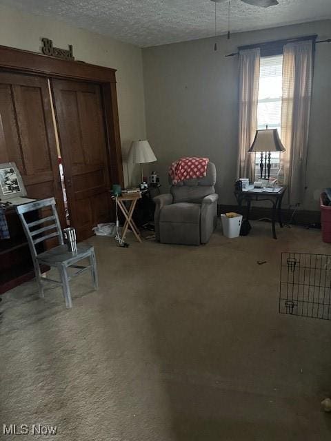 sitting room featuring carpet, ceiling fan, and a textured ceiling