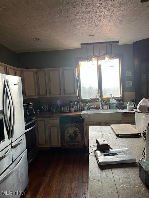 kitchen with black stove, sink, dark hardwood / wood-style floors, stainless steel fridge, and a textured ceiling