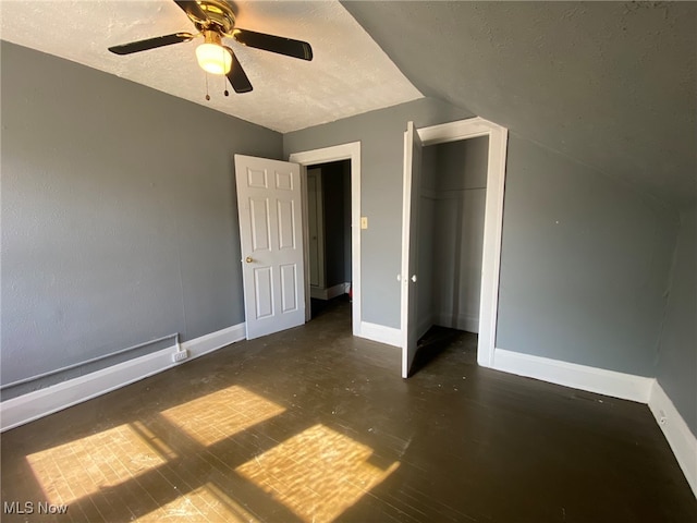 unfurnished bedroom featuring lofted ceiling, ceiling fan, a closet, and a textured ceiling