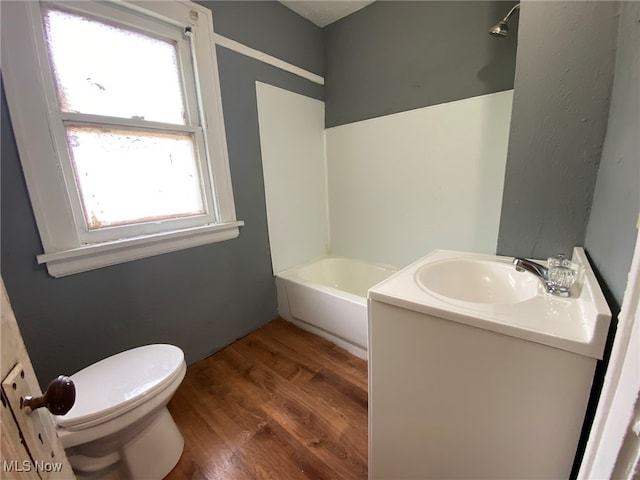 bathroom with vanity, a tub to relax in, hardwood / wood-style floors, and toilet