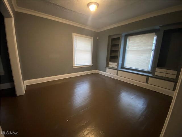 spare room featuring ornamental molding and dark wood-type flooring