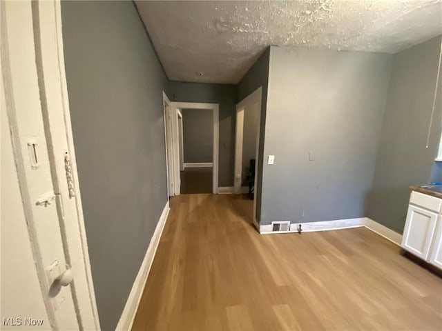 corridor featuring a textured ceiling and light hardwood / wood-style flooring