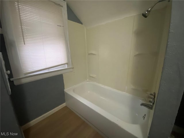 bathroom with hardwood / wood-style floors, vaulted ceiling, and shower / bath combination