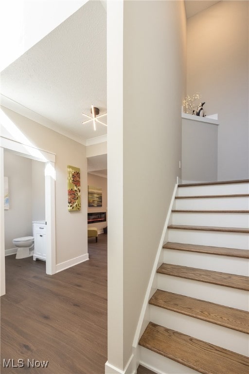 stairs with a textured ceiling, hardwood / wood-style flooring, and crown molding